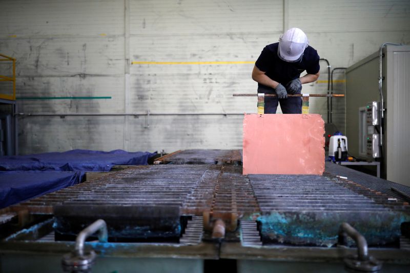 An employee holds a recycled copper plate at an urban