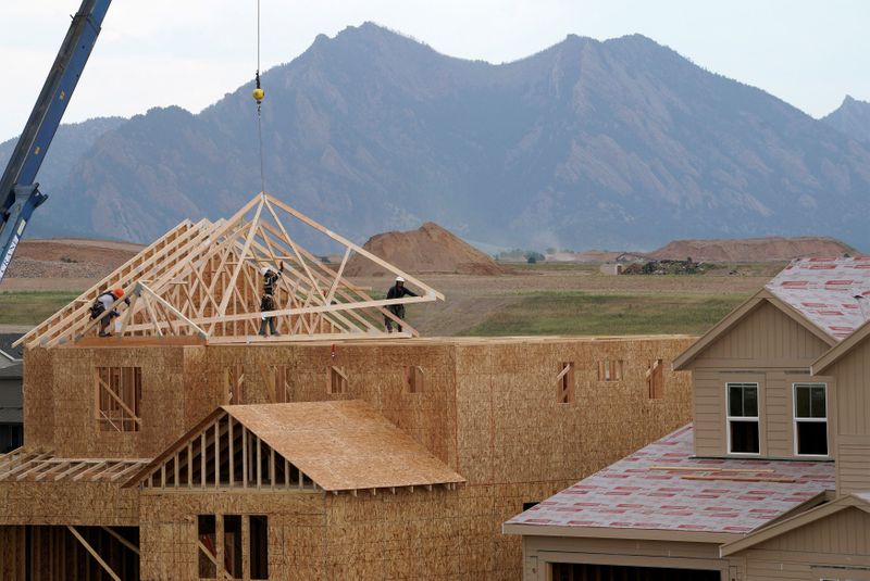 FILE PHOTO: Workers install roof trusses onto a new house