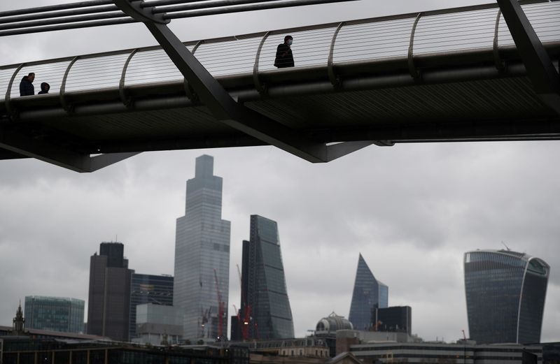 FILE PHOTO: People walk across Millennium Bridge with the City