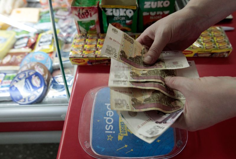 FILE PHOTO: A shop assistant demonstrates Russian rouble banknotes at