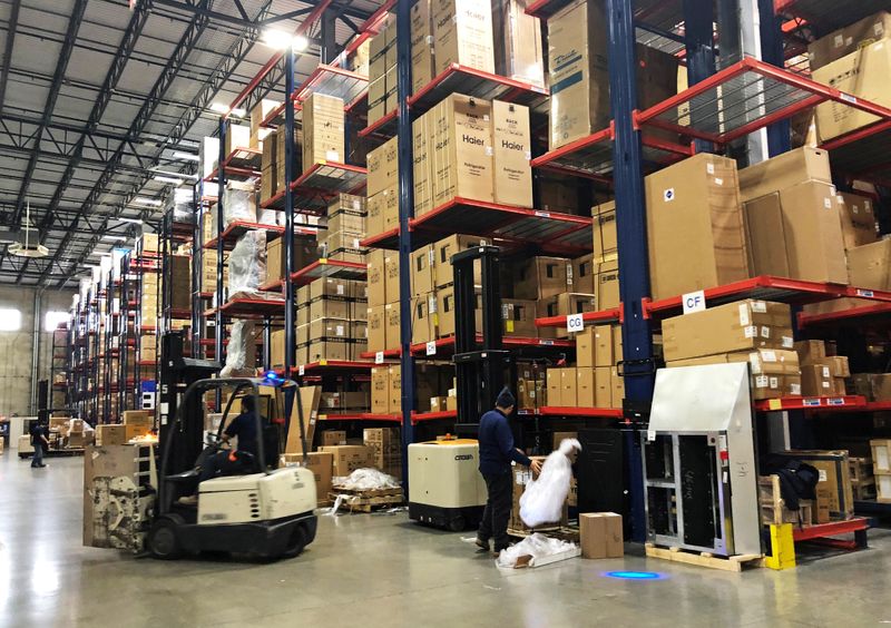 FILE PHOTO: Warehouse workers deal with inventory stacked up to