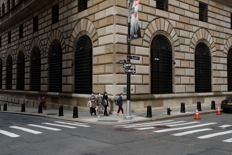 People walk wearing masks outside The Federal Reserve Bank of