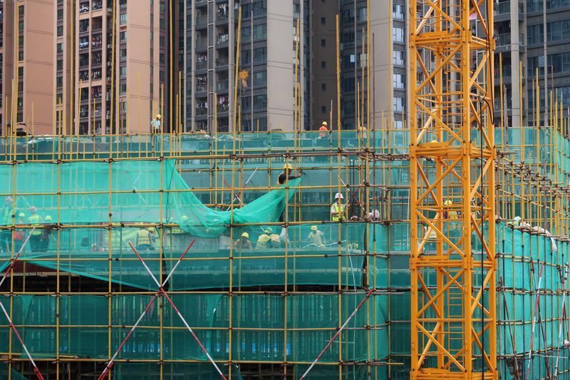 FILE PHOTO: Workers are seen on scaffoldings of a construction