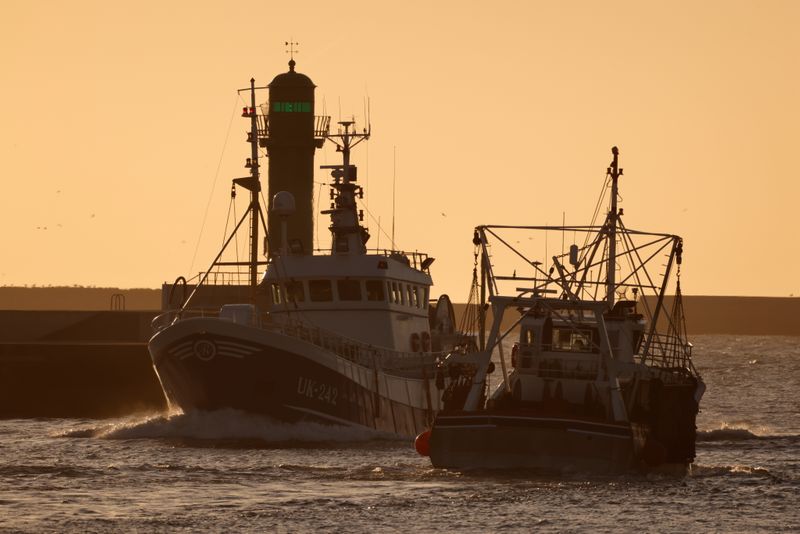 Trawlers are seen in the fishing port during sunset in