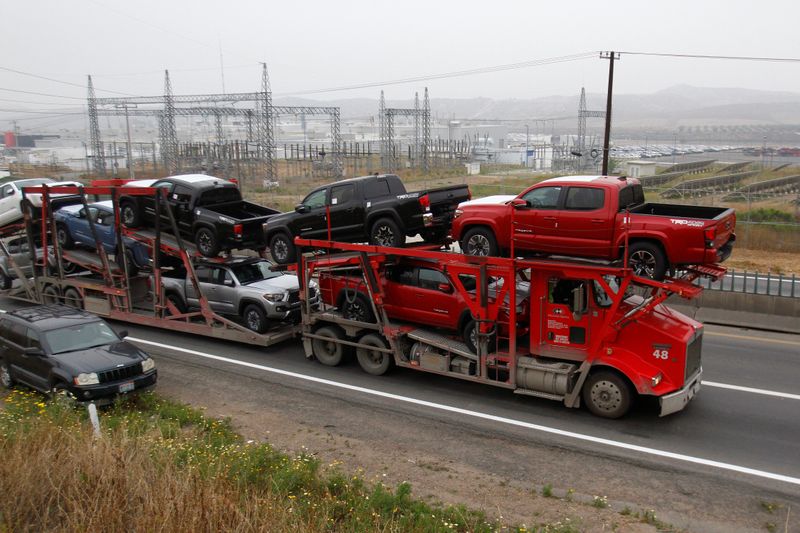 A carrier trailer transports Toyota cars for delivery while queuing