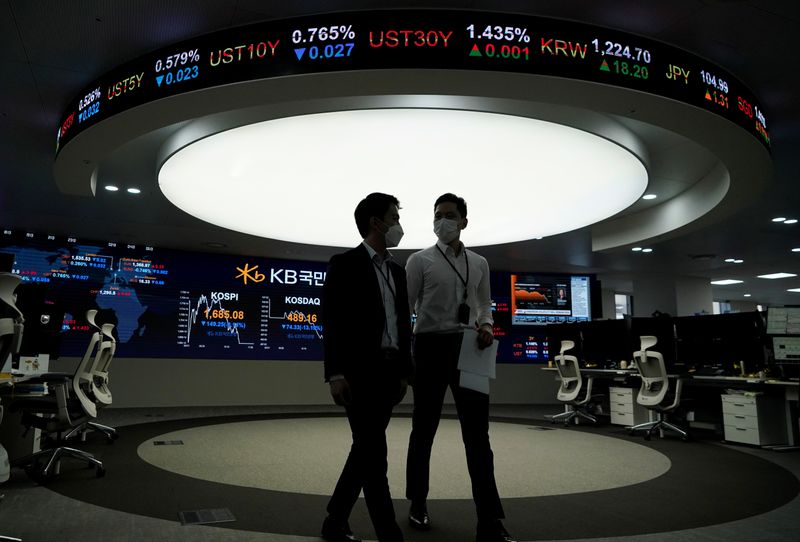 FILE PHOTO: Currency dealers walk past an electronic board showing
