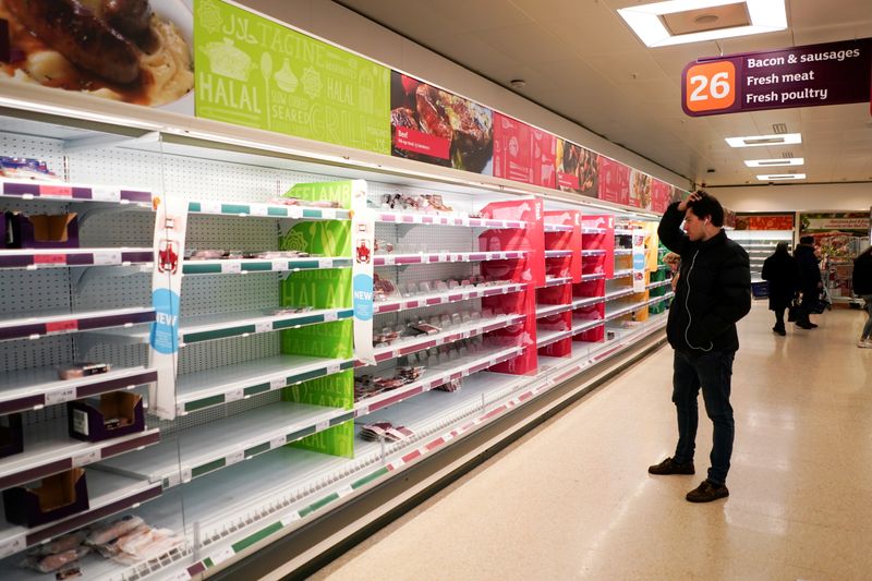 FILE PHOTO: A man stands next to shelves empty of