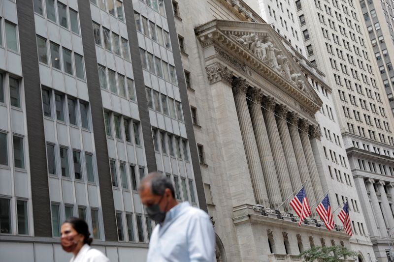 People wearing face masks walk by the NYSE during the