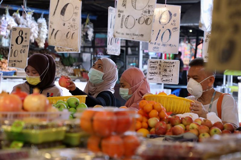 Shoppers wearing protective masks shop at a market, amid the