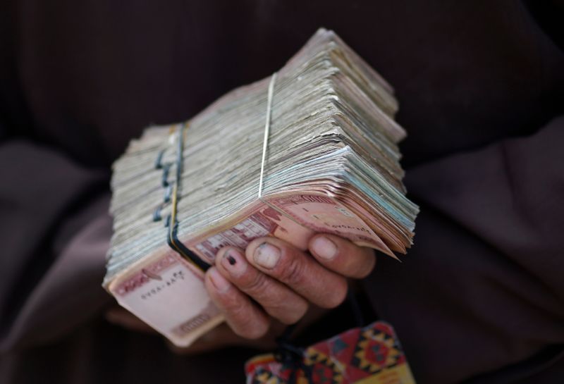 Money changer holds a stack of Afghan currency on a