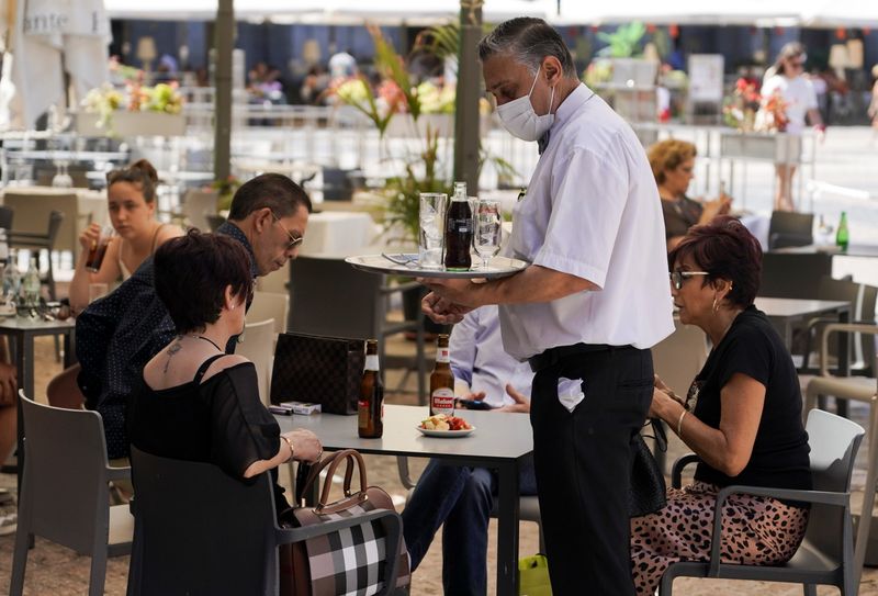 A waiter tends to customers on the terrace at a