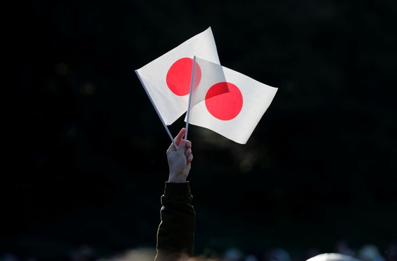 A well-wisher holds Japan’s national flags during Emperor Naruhito’s public