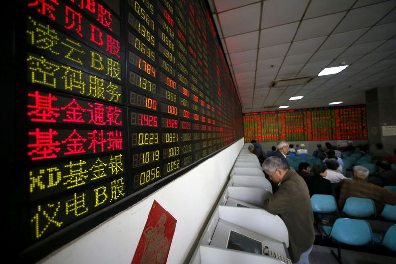 FILE PHOTO: Investors look at computer screens showing stock information
