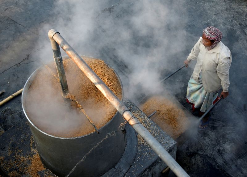 FILE PHOTO: A worker collects boiled rice to spread it