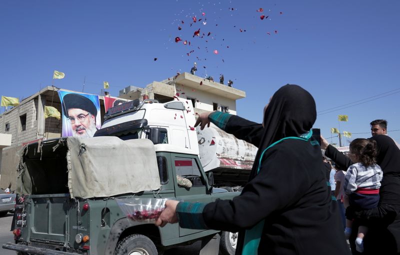 A woman throws flower petals and rice as a convoy