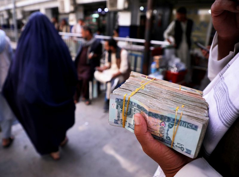 FILE PHOTO: Person holds a bundle of Afghan afghani banknotes