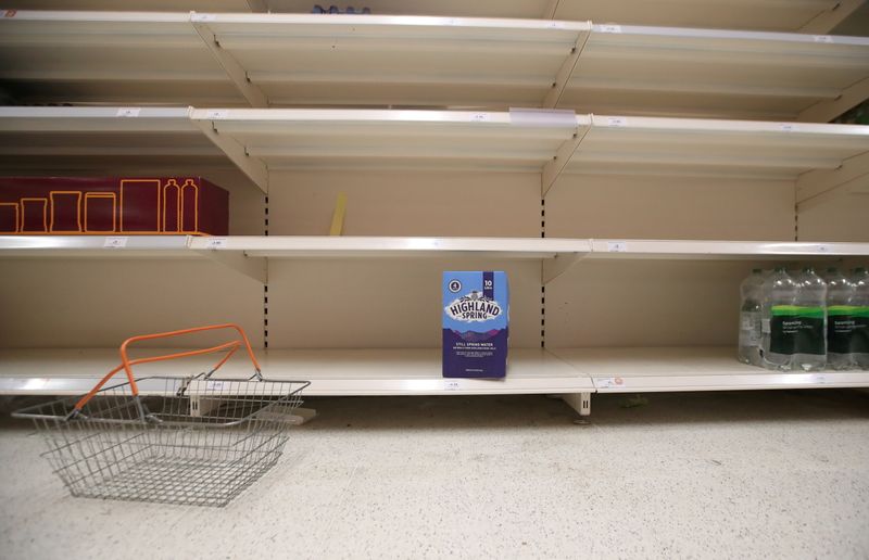 A shopping basket is discarded next to empty shelves of