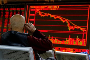 FILE PHOTO: An investor sits in front of a board