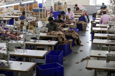 Workers stitch garments at a factory of an apparel shop