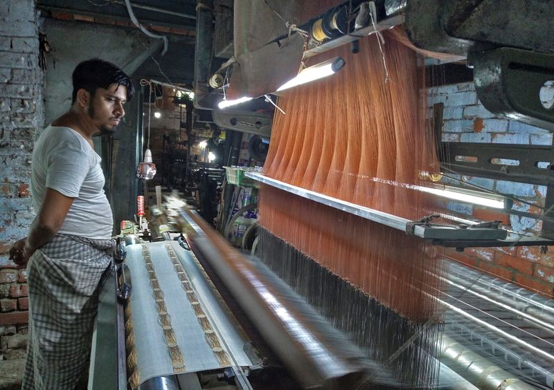 A weaver works on a power loom at factory in