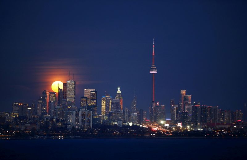 FILE PHOTO: The moon rises behind the skyline and financial