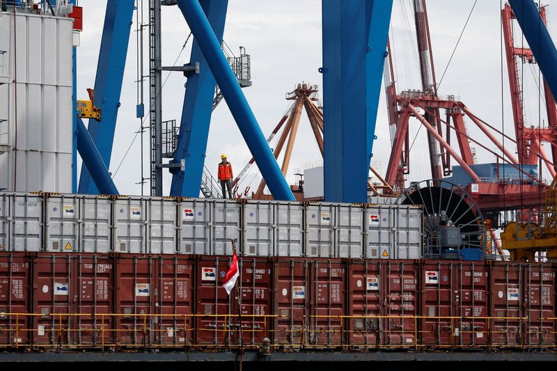 FILE PHOTO: A worker stands on a container at Tanjung