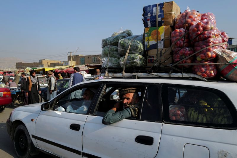 A man rides a car filled with vegetables and fruits