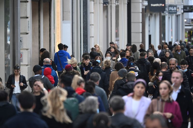 Shoppers, some wearing masks, walk along Oxford Street amidst the