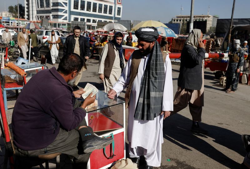 Afghan currency exchange dealer checks banknotes at the market in