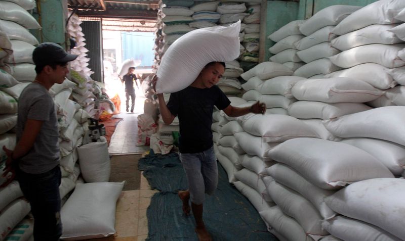 A worker carries a bag of rice to a store