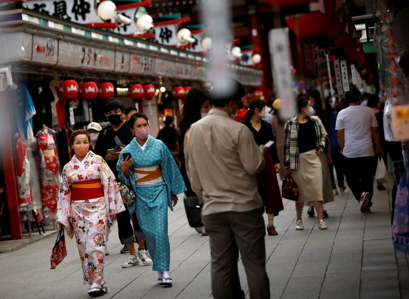 Kimono-clad tourists wearing protective face masks walk along Nakamise Street