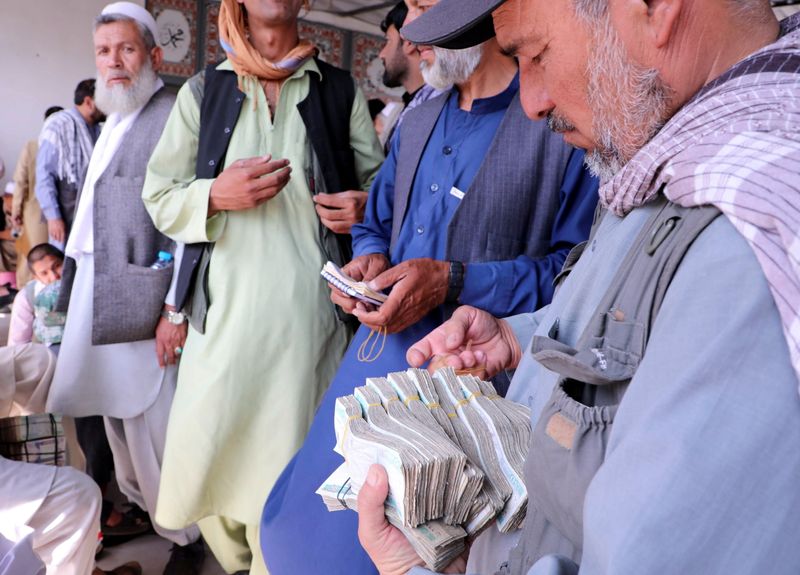 FILE PHOTO: Afghan money exchange dealers wait for customers at