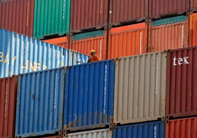 FILE PHOTO: A worker sits on a ship carrying containers