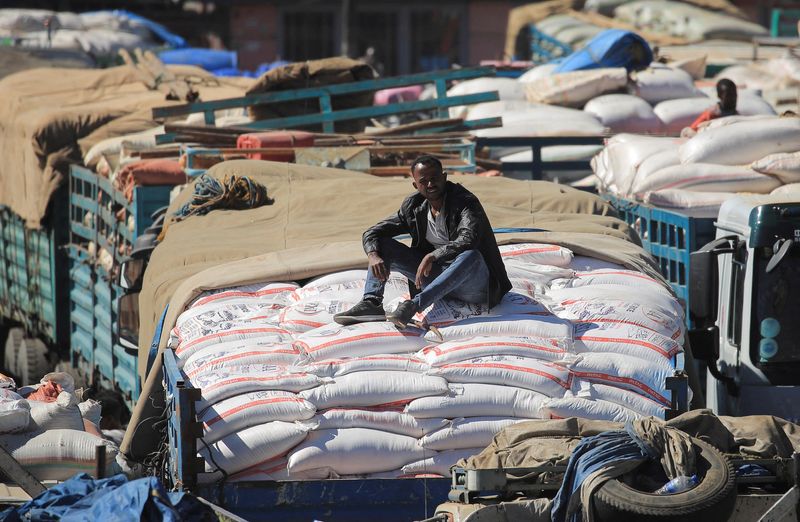 Labourer sits atop a truck queuing with sacks of grains