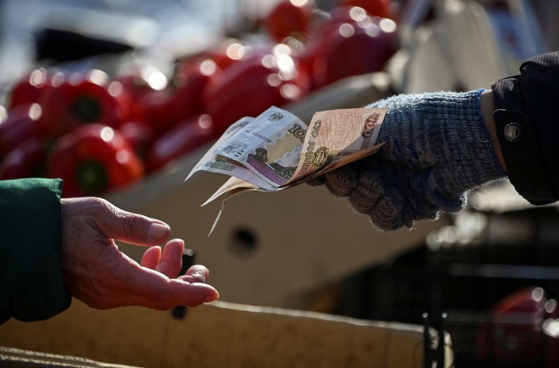 A vendor hands over Russian rouble banknotes to a customer at a