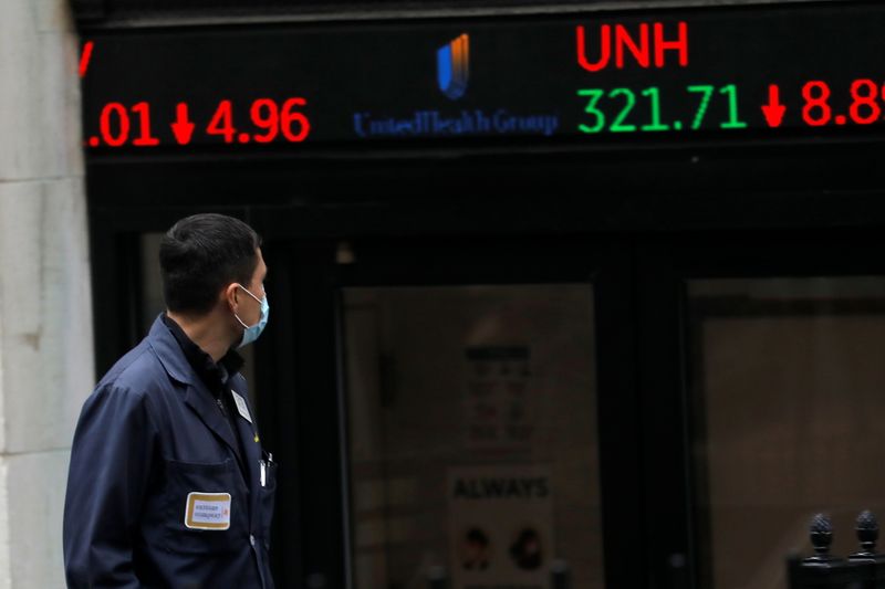 A trader walks past a digital stock price display outside