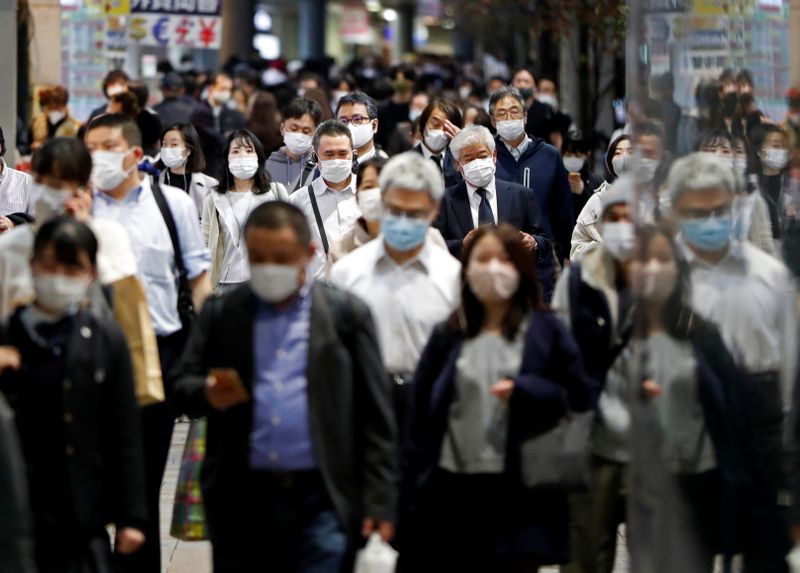 People wearing protective face masks walk on the street, amid