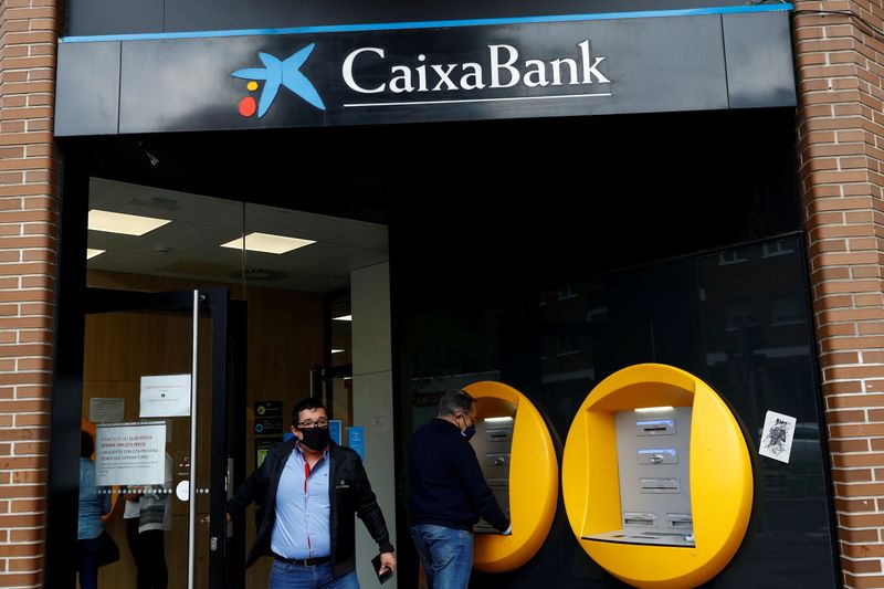 FILE PHOTO: A person walks out of a Caixabank’s bank