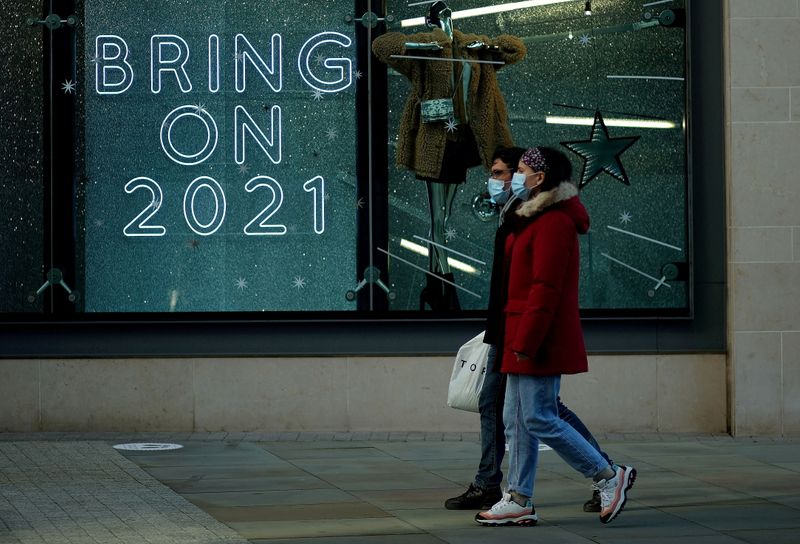 FILE PHOTO: People walk past a sign in a shop