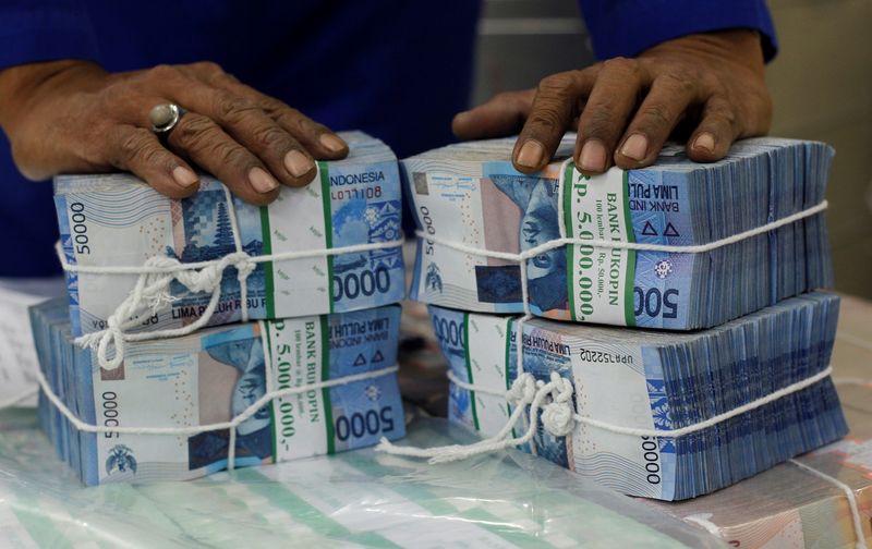 FILE PHOTO: A worker prepares bundles of rupiah bank notes