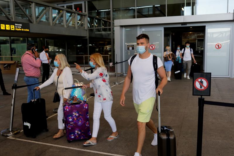 FILE PHOTO: Tourists wearing protective face masks walk with their
