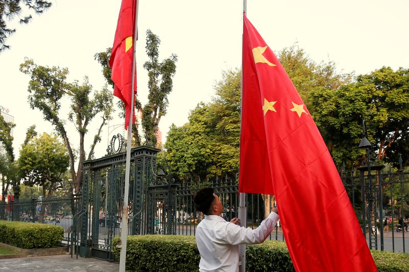 A man raises a Chinese flag next to a Vietnamese