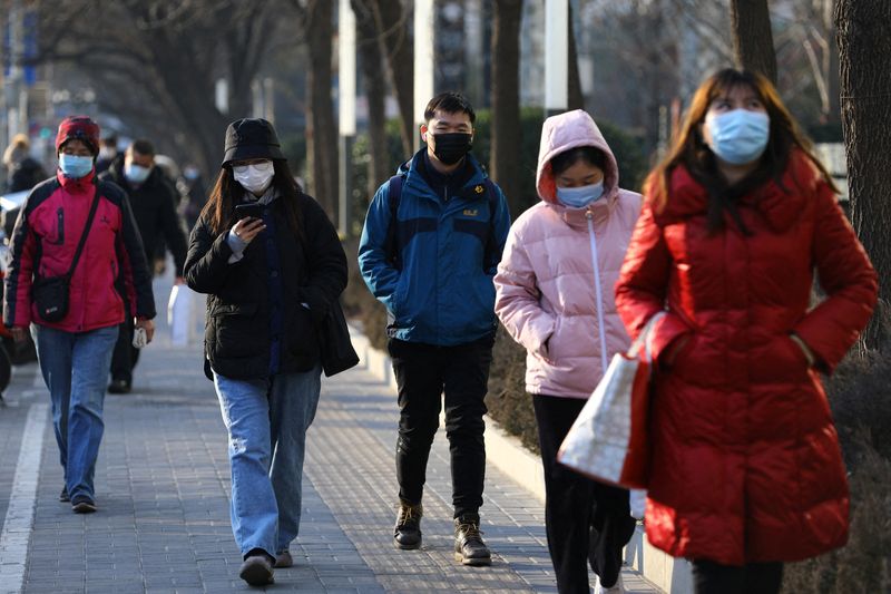 People wearing protective face masks walk on a street during