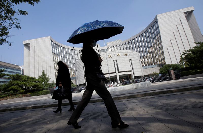 People walk past the headquarters of the PBOC, the central