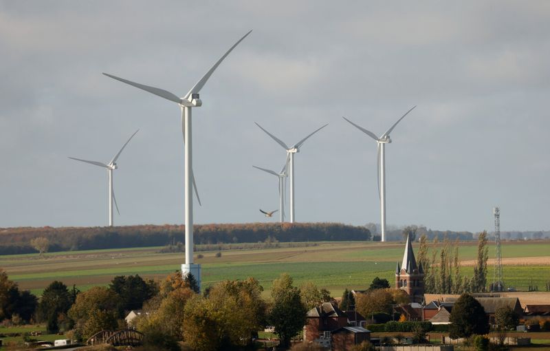 Power-generating windmill turbines are seen behind church in village of