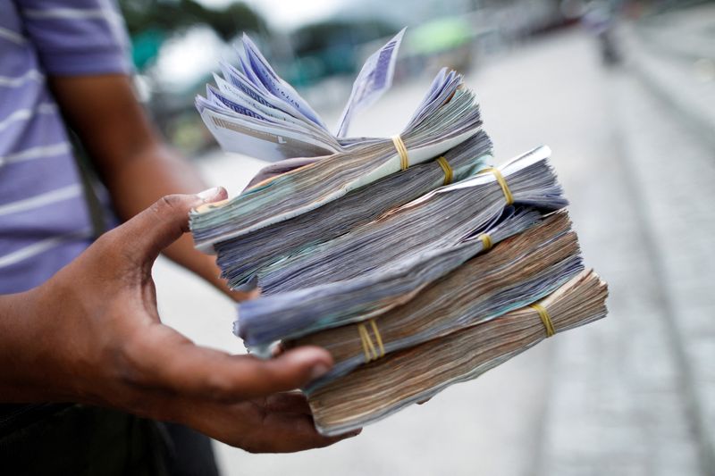 FILE PHOTO: The assistant of a bus driver holds Bolivar