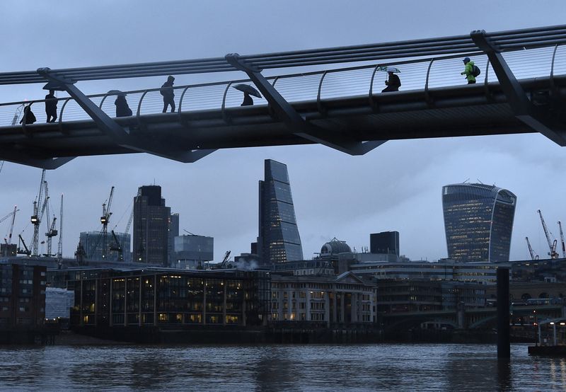 City workers cross the Millennium footbridge in the financial district