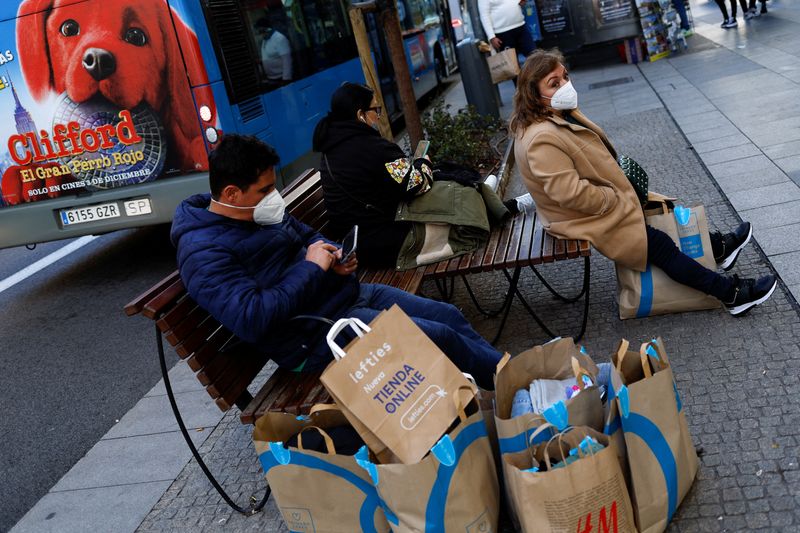 People sit next to shopping bags during winter sales in