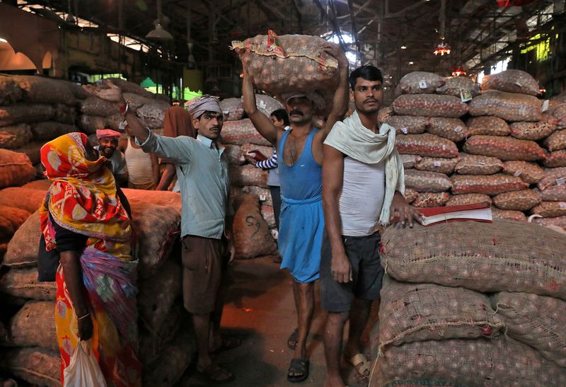 FILE PHOTO: Labourer carries sack of onions at wholesale market