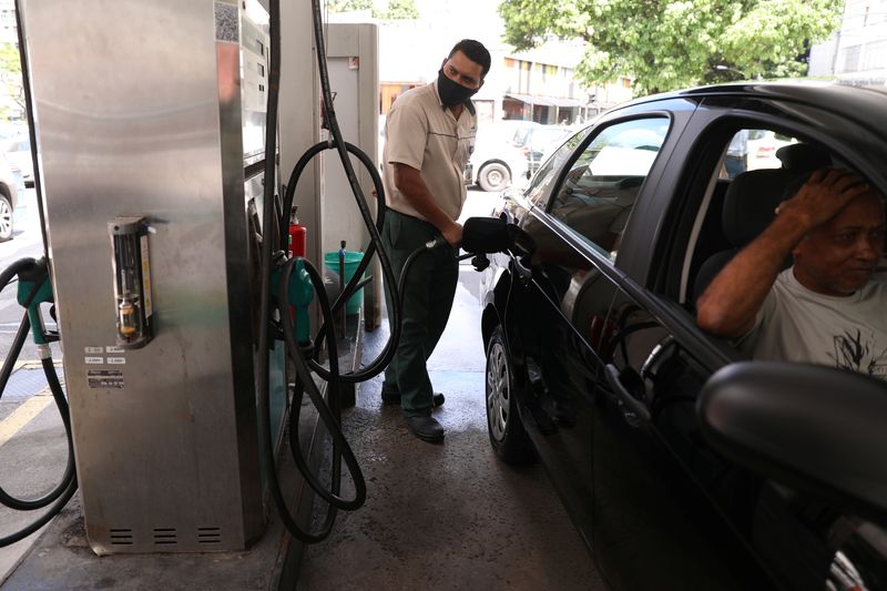 A worker pumps a car with gasoline at a gas